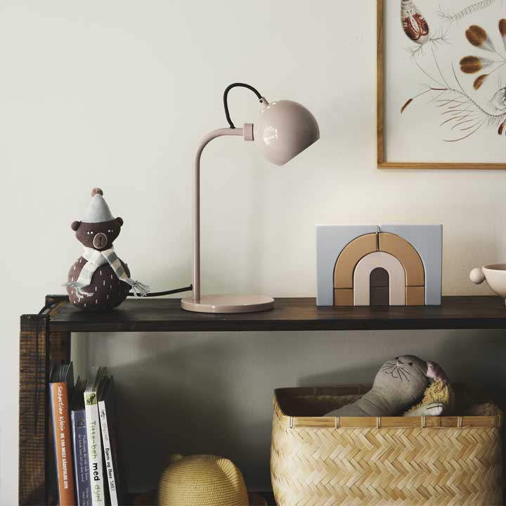 Urządzamy dom, lampa stołowa Ball Single obok na półce dekoracje, książki i koszyk, na ścianie fragment obrazu.